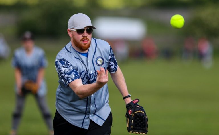 Close-up action shot of Jack with glove extended catching or releasing a pitch, wearing a blue kit on a grass field