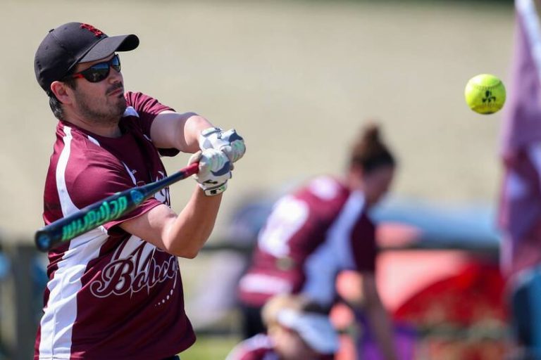 Close-up action shot of Olaf completing a batting swing in maroon kit and sunglasses