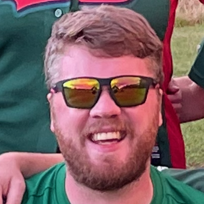 Close portrait of Dales player Rob wearing mirrored sunglasses and smiling, in green kit with other players visible behind