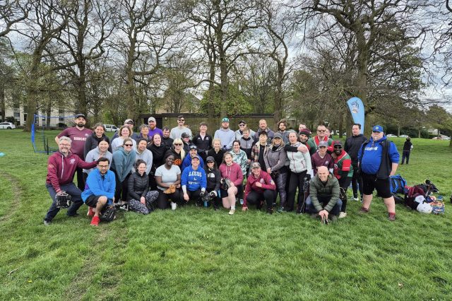 Large mixed group of players standing together at the Shake and Bake session in April 2024, trees and open parkland in the background
