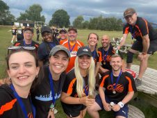 Coyotes players in orange kit taking a group selfie at a fun day or awards event, someone holding a trophy visible in the background
