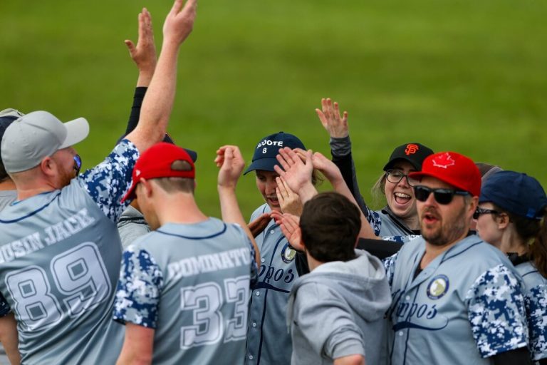 Baseball team celebrates together on field in gray uniforms with blue and white digital camo sleeves