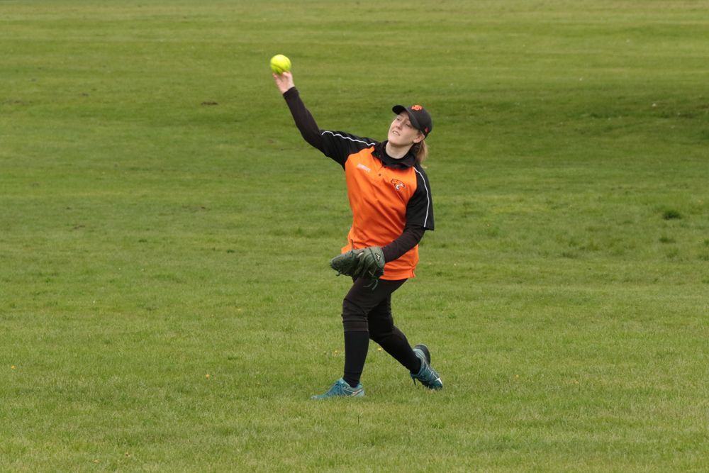 Orange Bib Fielding Catch Player in an orange training bib reaching up to catch a softball in the field, arms outstretched on a green pitch