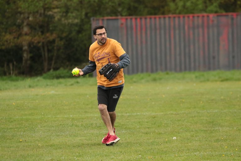 Player in yellow and black kit diving or reaching to catch a ball in the outfield on a lush green pitch