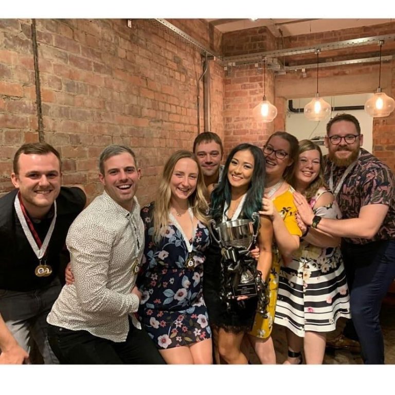 Group photo at an LSA awards social evening, players dressed up and gathered in front of an exposed brick wall
