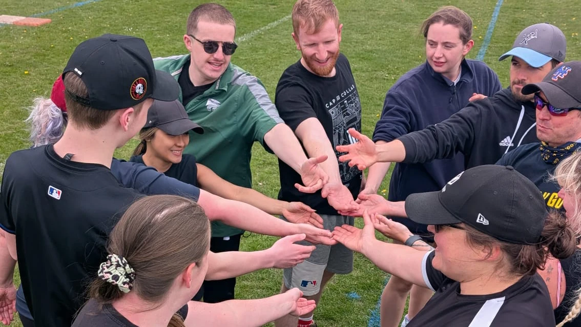Bad Batch team players putting hands in for a team huddle circle, wearing dark kit