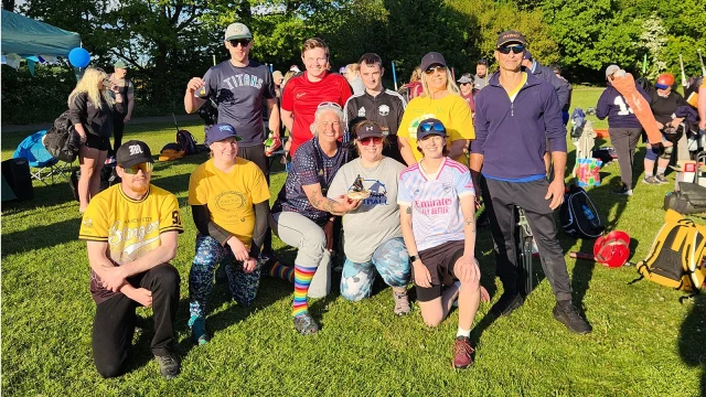 Cheeze team group photo in mixed clothing with yellow accents, gathered on a grass field in evening light
