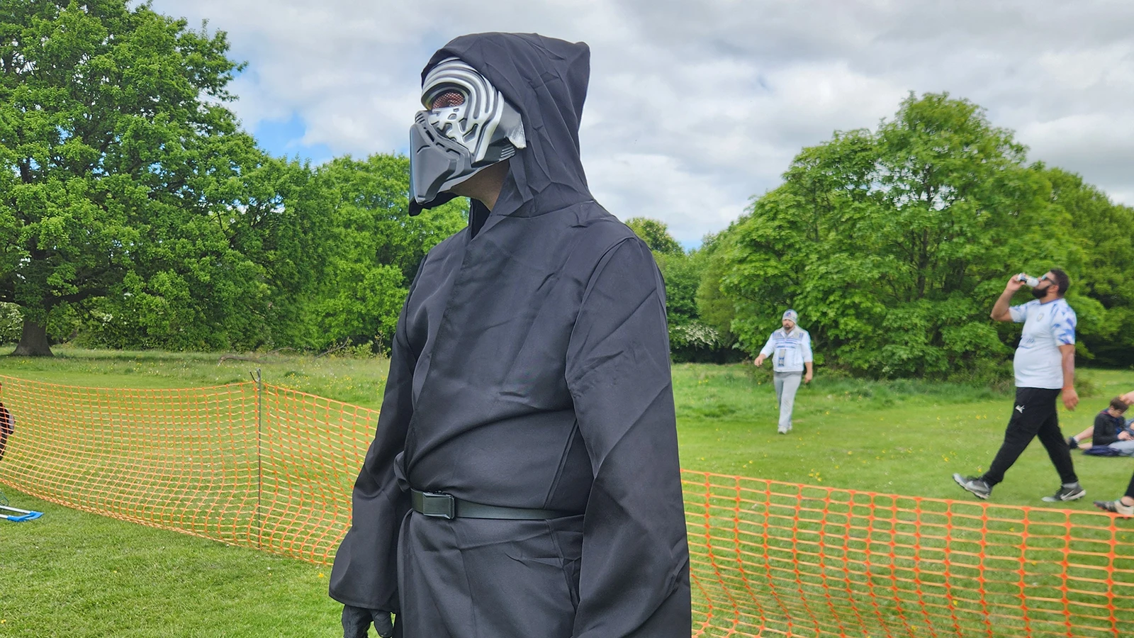 Person in a full black Kylo Ren Star Wars costume standing on a grass field at a tournament event