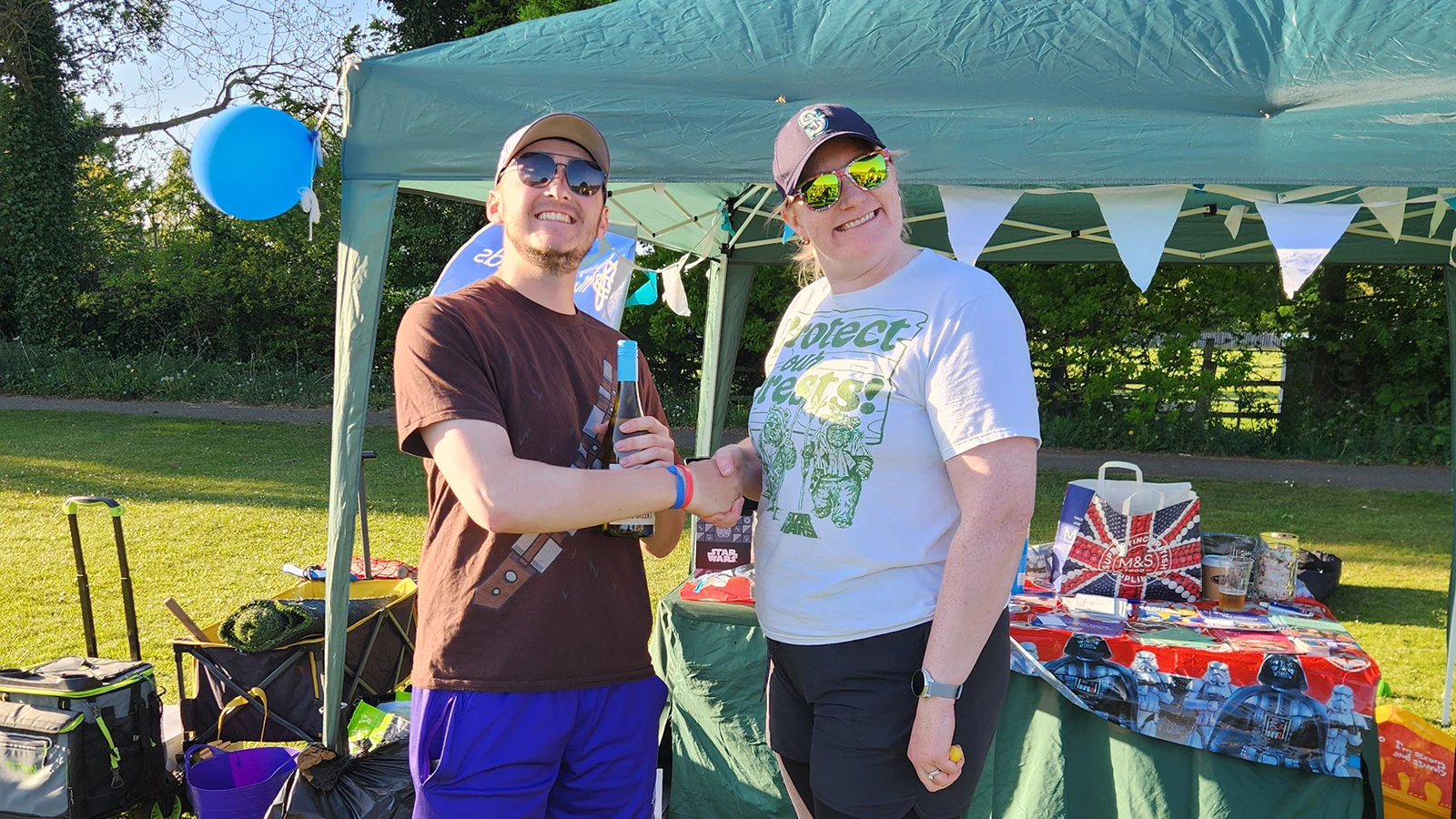 Two players at the Leeds tournament MVP award presentation under a marquee, one in a colourful jersey